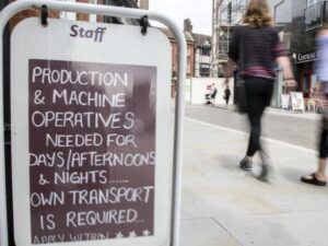 People in street walking past job board