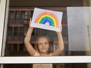 Photo of girl at window with rainbow drawing
