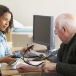 An older man has his blood pressure measured by a GP