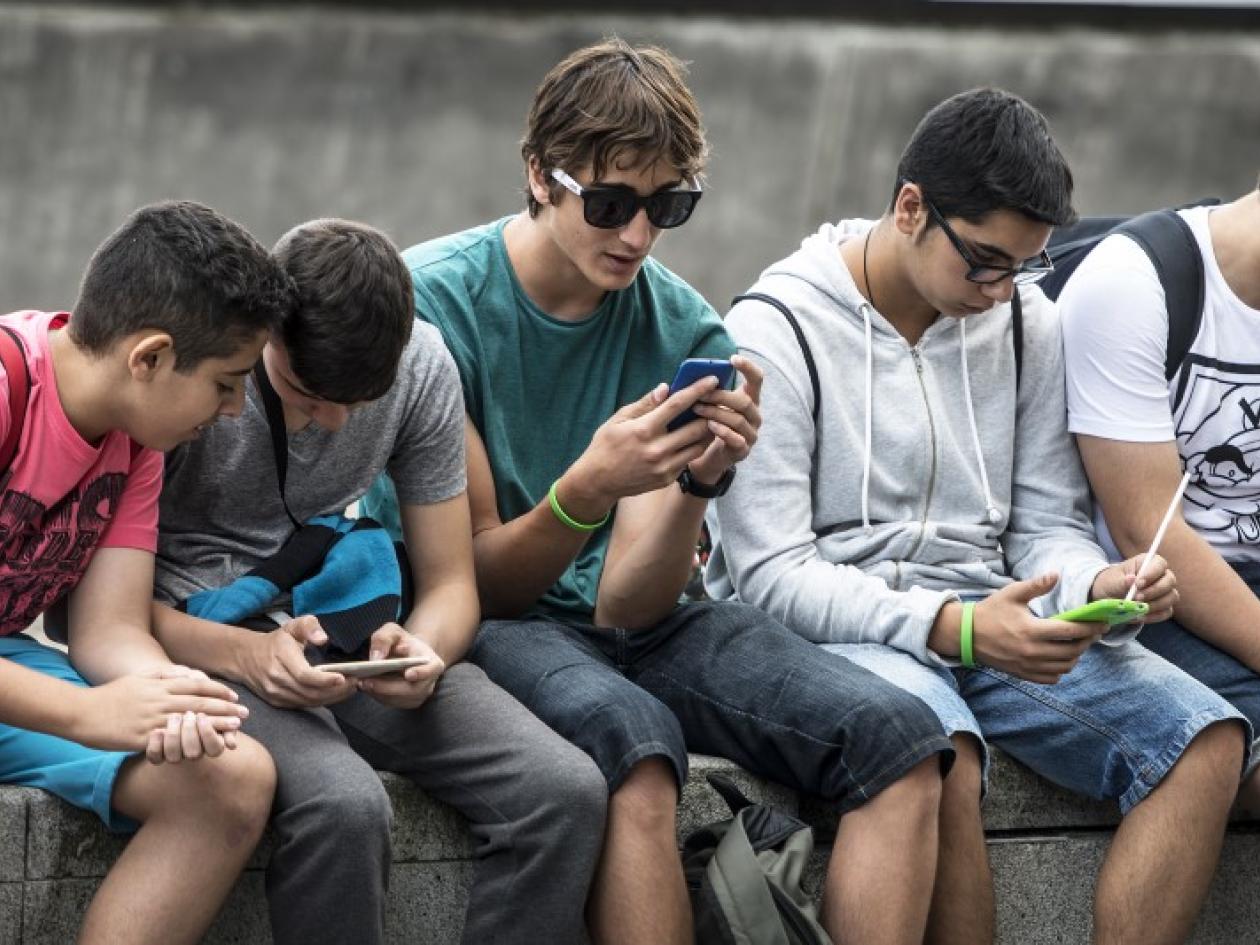 a row of teenage boys looking at phones