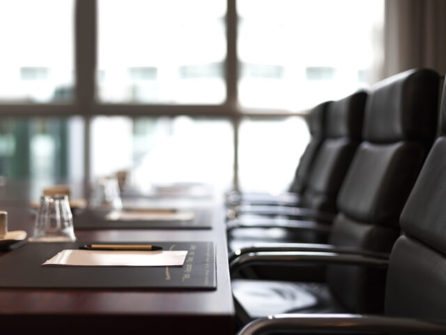 Photo of empty chairs at a meeting table.