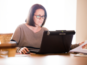 A woman sits at a table on her laptop