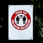 A sign in a window reading "Thank you for social distancing", illustrated with two human figures standing 2m apart