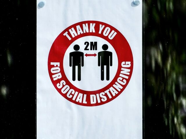 A sign in a window reading "Thank you for social distancing", illustrated with two human figures standing 2m apart