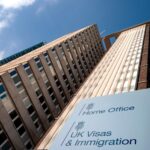 Shot looking up at office blog. Sign outside building reads "Home Office - UK Visas and Immigration"