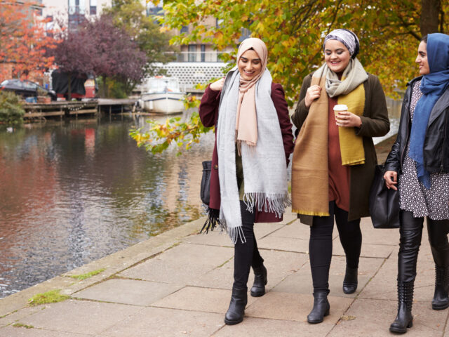 Three young Muslim women walking by a canal