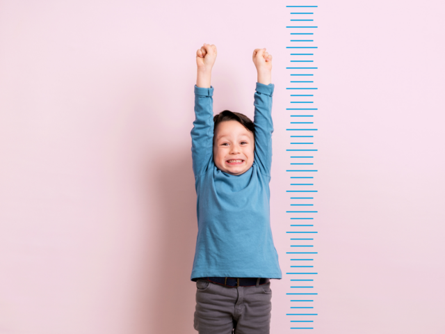Small boy next to a height chart