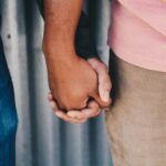 close up of two men holding hands by Jenna Jacobs on Unsplash