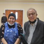 A female carer in plastic gown and older male care recipient