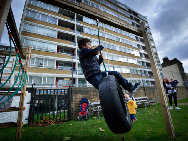 Photo of a child on a tyre swing in a playground.